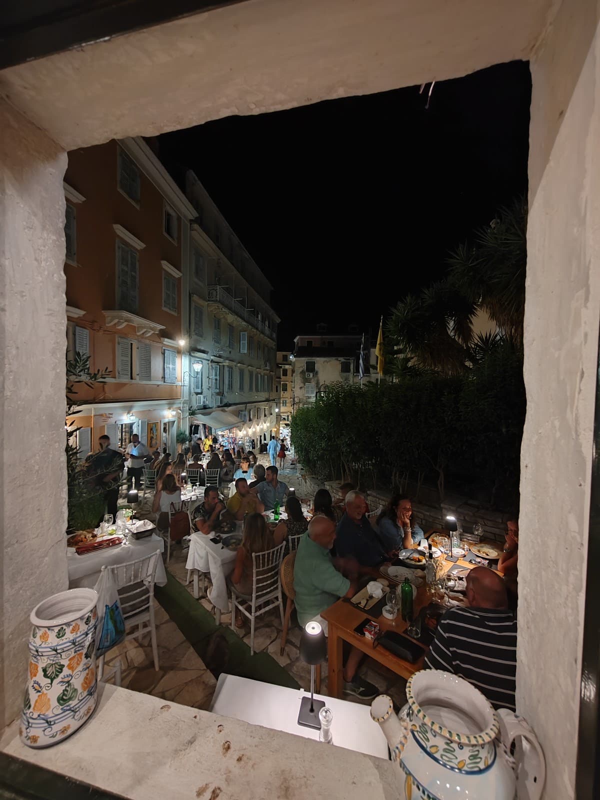 View through a stone window of MeZen's bustling terrace at night